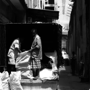 Laborers unloading white bags from truck