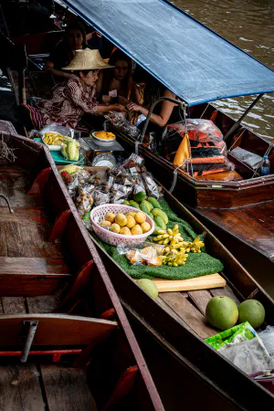 Vendor on a boat selling fruits to tourists on another boat