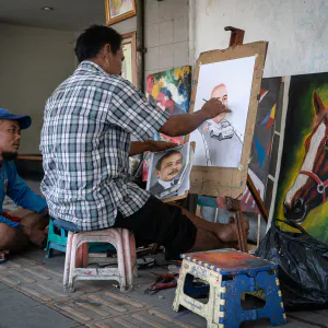 Man painting a portrait in the sidewalk