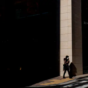 Woman walking in front of a shadowed building