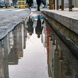 Couple reflected in a puddle of water in Ginza