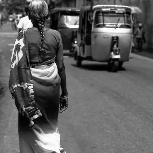 Three wheelers passing by woman with saree