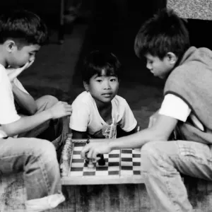 Boys playing chess by roadside