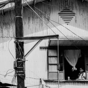 Woman watching bicycle race through upstairs wiindow