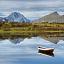 En båt i et vann i et naturlandskap med en hytte i Lofoten.