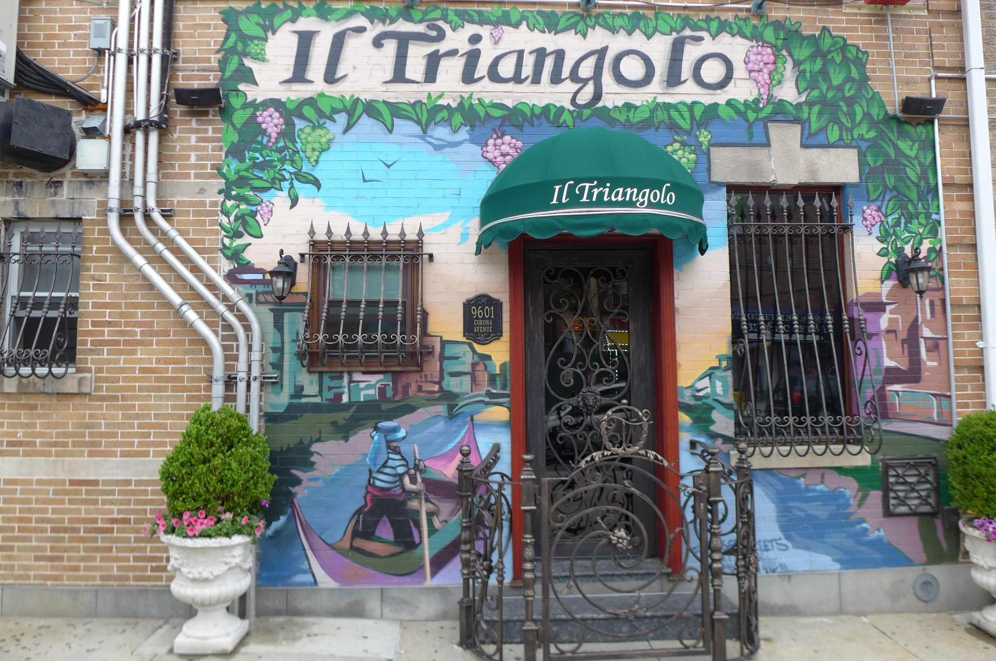 The exterior of a restaurant with a painted mural depicting an Italian riviera scene