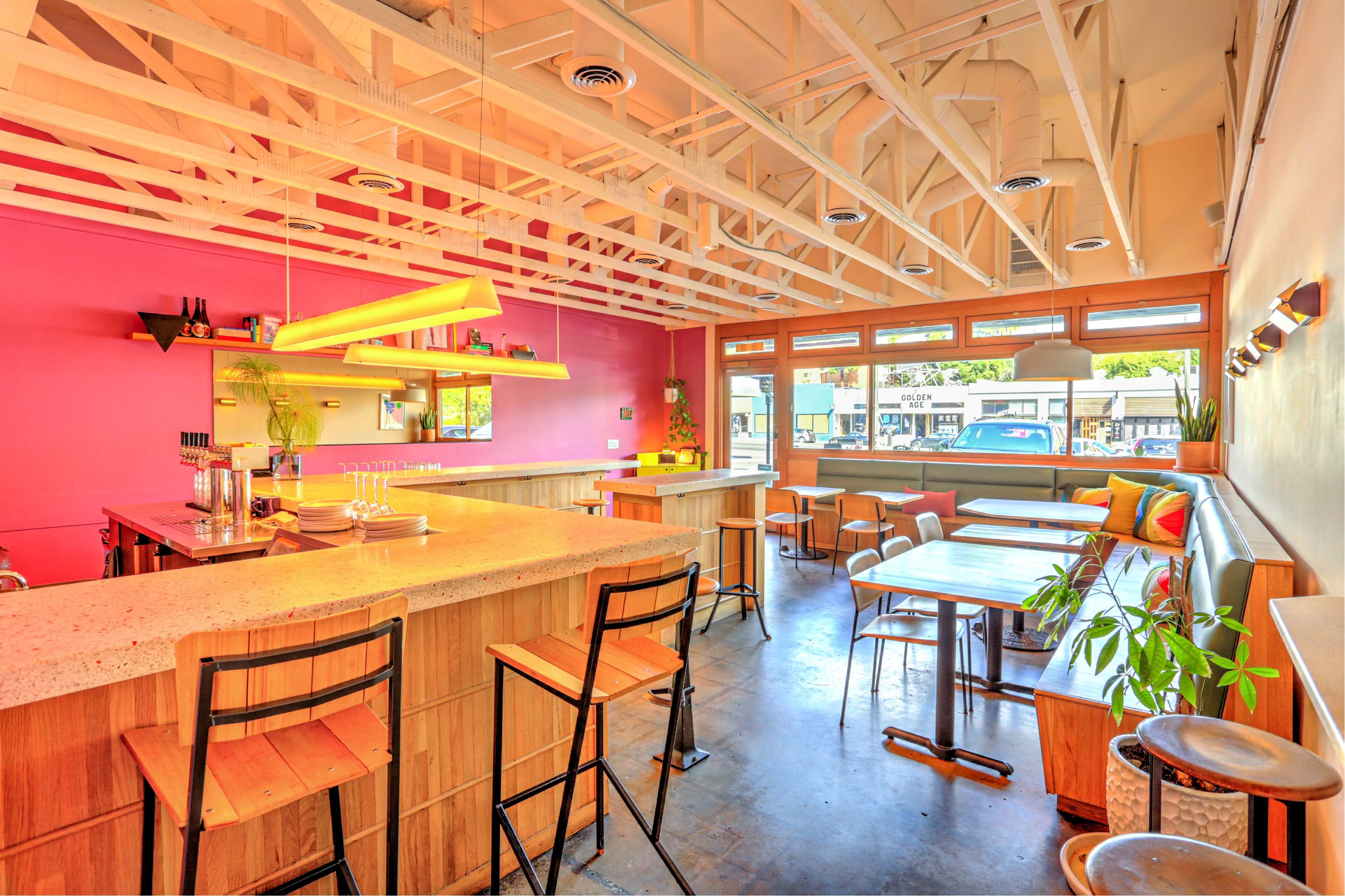 An interior shot with tables, chairs, and a large window at the Ruby Fruit natural wine bar in Silver Lake, California.