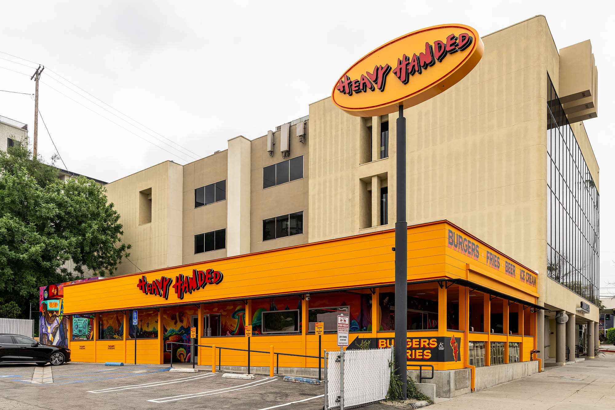 The parking lot and orange and red exterior for Heavy Handed restaurant in Studio City, California.