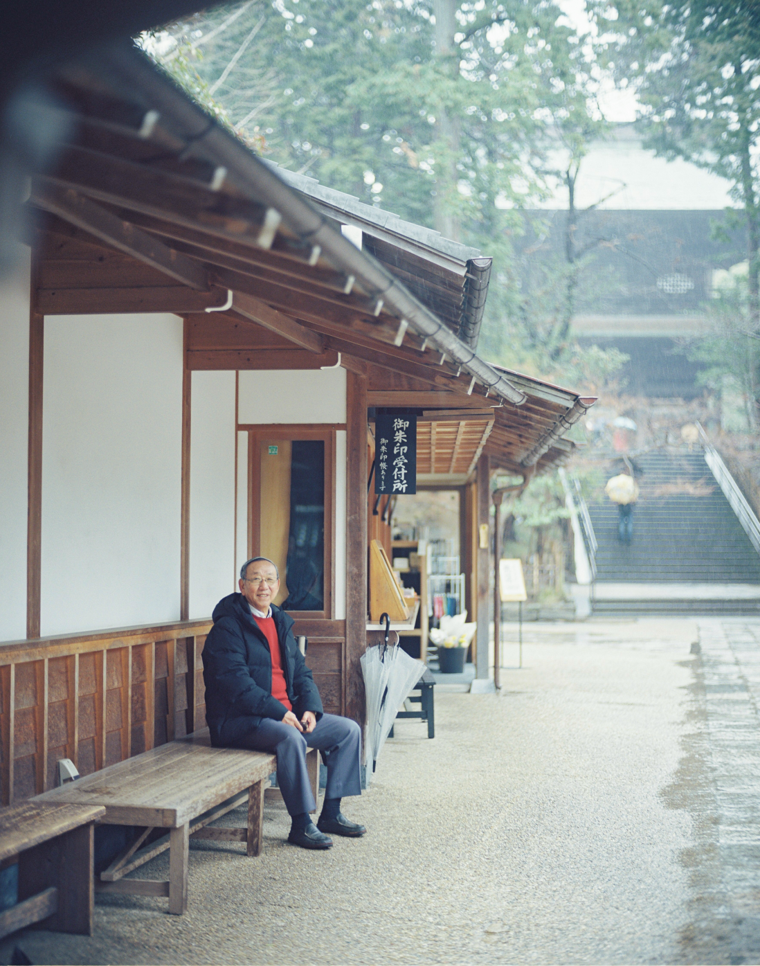 御朱印受付所の横にあるベンチに座っている笑顔の男性。