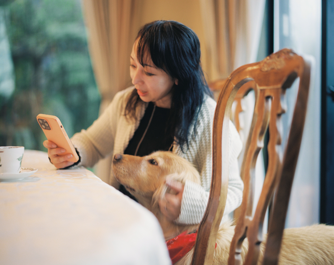 右手に携帯電話を持ち、画面の見る女性とわんちゃん。