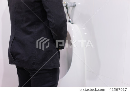 Businessman peeing to toilet bowl in restroom. 41567917