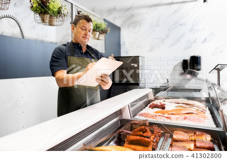 seller with clipboard selling seafood at fish shop 41302800