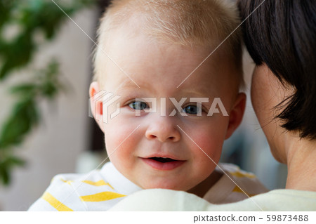 Portrait of a cute little smiling baby boy looks out over the mother shoulder 59873488