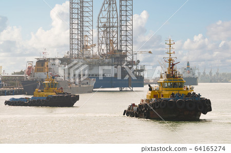 Tug boats awaiting big cargo ship in harbour for 64165274