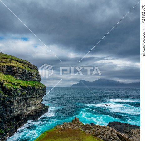 Rough coastline in Faroe Islands with tourists 72482970