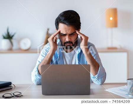 Stressed Eastern Businessman Suffering From Headache Or Business Problems At Workplace 74564209