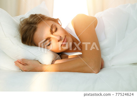 Beautiful blonde girl sleeping sweetly in sunny bedroom on a white bed. Holyday comfort and Rest concepts 77524624