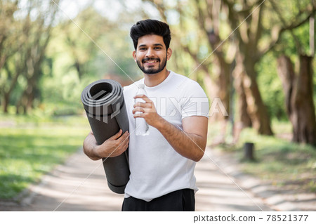 Smiling arab man in sport clothes drinking water at park 78521377