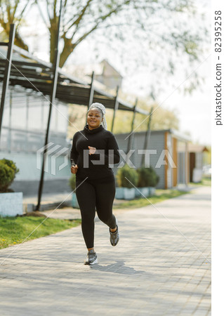 Afro-american plus size woman jogging outdoor 82395258