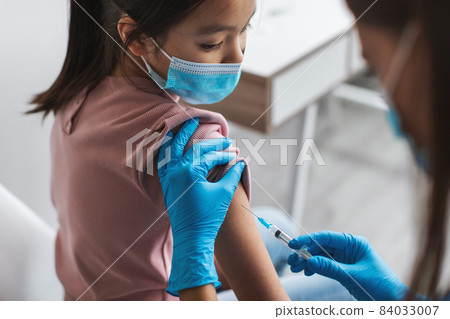 Nurse Injecting Covid-19 Vaccine Vaccinating Korean Little Girl Sitting Indoor 84033007