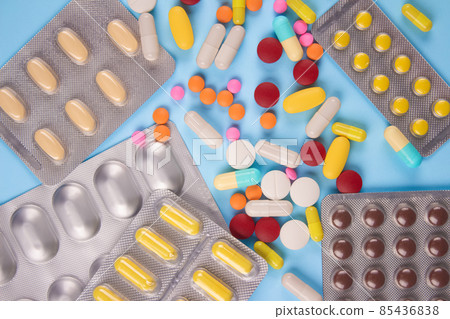 Assorted multicolored medicine pills, capsules and tablets in blisters on blue background. Variety of immune system vitamins and supplemets. Dietary bio supplements 85436838