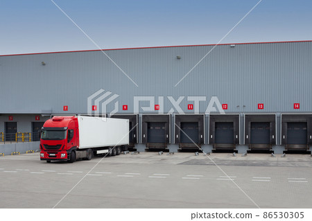 Unloading trucks at a modern warehouse complex. 86530305