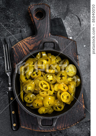 Pickled Green Sliced Jalapenos in a pan. Black background. Top view 86840050