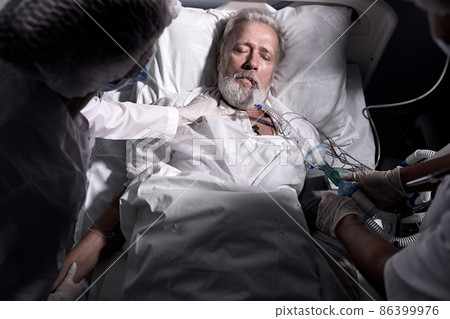 Team of doctors caring of sick patient in resuscitation, senior man lying on bed 86399976