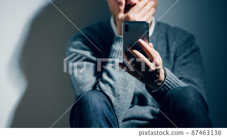 A man with a mental illness is using a smartphone 87463136