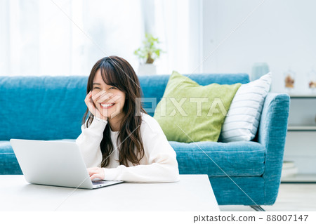 A young woman looking at a computer in the living room 88007147