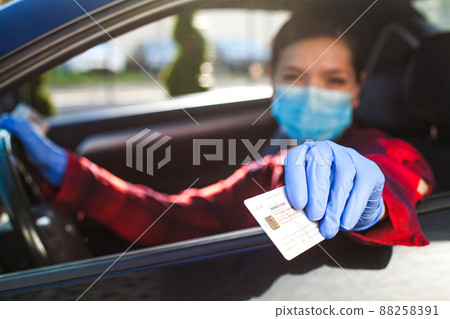 Young female driver showing Coronavirus health card or immunity passport 88258391