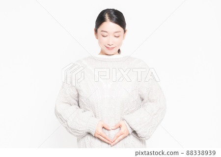 A woman standing in front of a white background with her hands on her belly 88338939