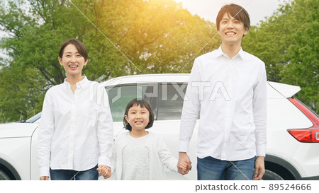 Family holding hands in front of the car 89524666