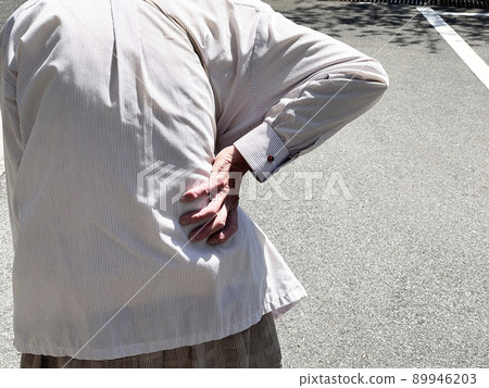 Hands of an elderly woman holding her hips_Asphalt background 89946203