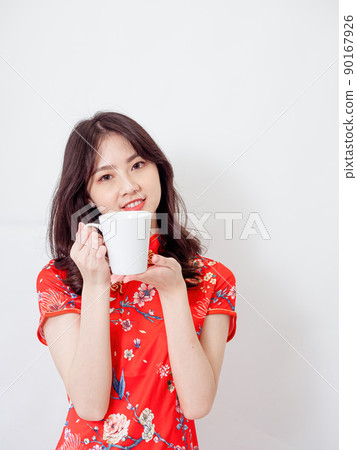 Portrait of young asian woman wearing traditional cheongsam qipao dress relaxing drinking on white background. 90167926