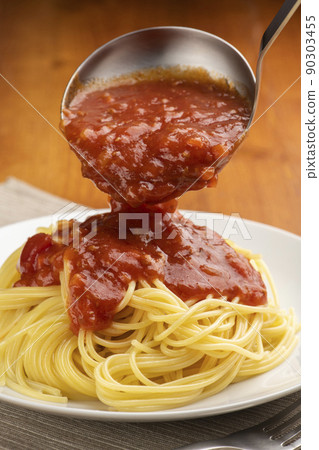 I'm preparing a meal by sprinkling meat sauce on pasta with a sauce ladle. 90303455