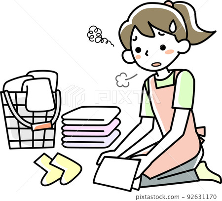 A young woman folding laundry with a tired expression 92631170