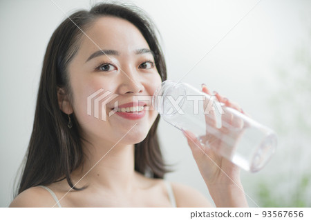 A teenage Japanese woman hydrating with a water bottle 93567656