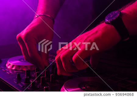 Dj mixing on turntables with color light effects. Soft focus on hand. Close-up. 93694868