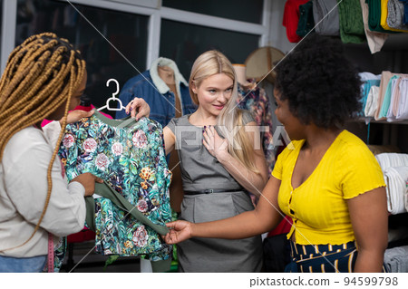 The saleswomen convince the blonde that this blouse is just for her. 94599798