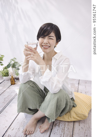 Young woman drinking water in the living room 95561747