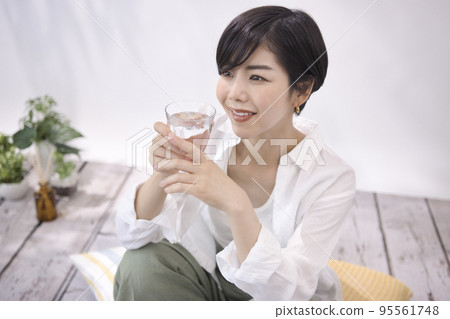 Young woman drinking water in the living room 95561748