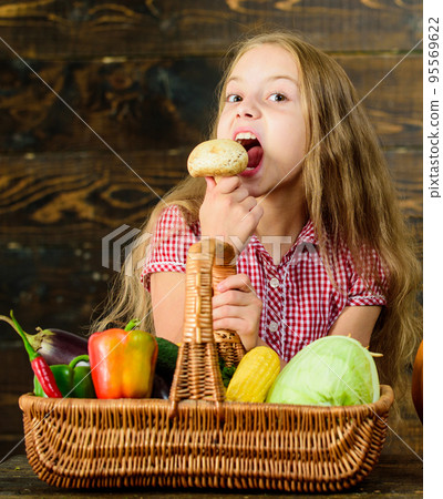 Kid girl near basket full of fresh vegetables harvest rustic style. Harvest festival concept. Farm market fall harvest. Child girl presenting harvest of her vegetable garden on wooden background 95569622