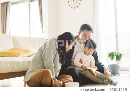 Child-rearing image of a family reading a book in the living room and a boy 95611929