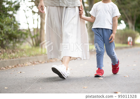 Parent and child walking hand in hand 95011328