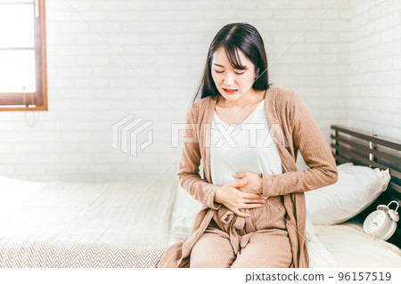 Japanese woman suffering from abdominal pain and menstrual pain in the bedroom 96157519