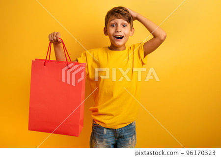 Happy child are amazed about a shop sales. surprised, expression. Yellow background color 96170323