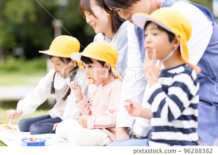 A nursery teacher and a child who eat lunch in the park 96288382