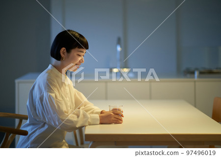 Young woman drinking water in calm room 97496019