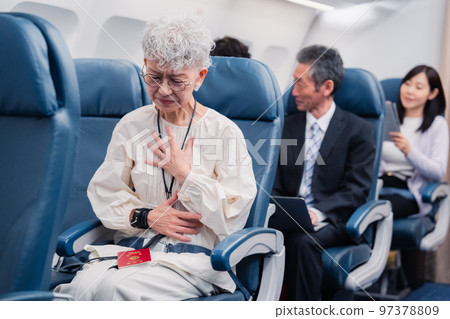 An elderly woman suffering from poor physical condition on an airplane 97378809